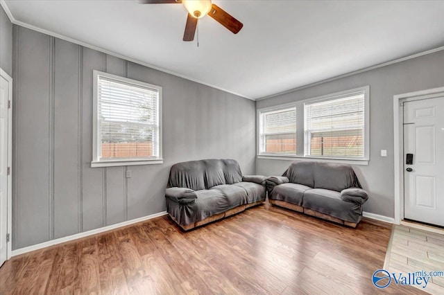 living room with a ceiling fan, baseboards, ornamental molding, and wood finished floors