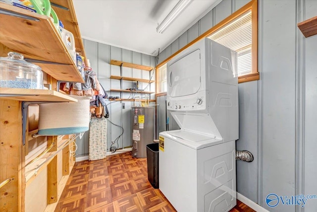 clothes washing area featuring water heater, stacked washer and dryer, and laundry area