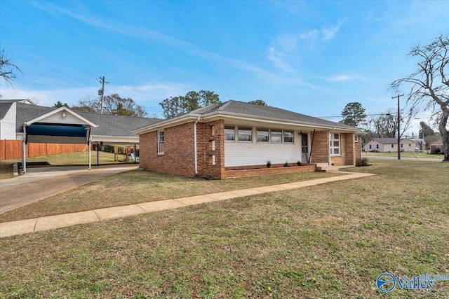 view of front facade with a carport, a front yard, concrete driveway, and brick siding