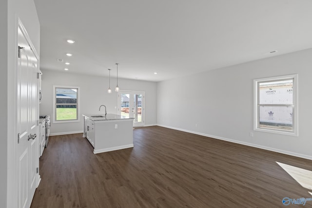 kitchen with an island with sink, pendant lighting, dark hardwood / wood-style flooring, white cabinets, and sink