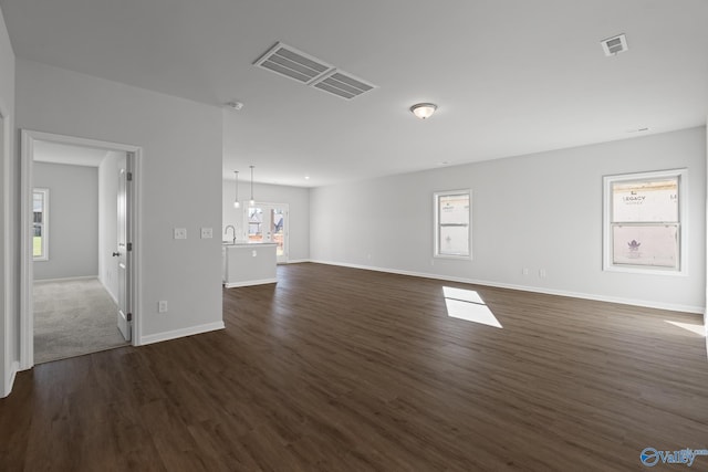 unfurnished living room featuring sink, a wealth of natural light, and dark hardwood / wood-style floors