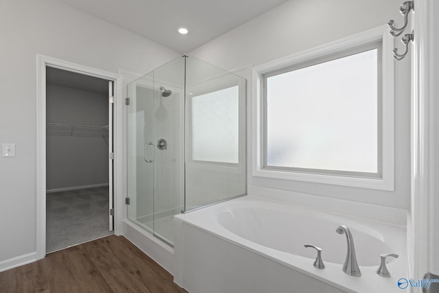 bathroom with independent shower and bath and wood-type flooring