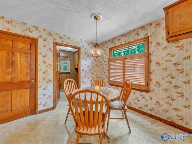 1913 Ruth St, Scottsboro, AL 35769 - dining room featuring a textured ceiling, a chandelier, baseboards, wallpapered walls, and light floors
