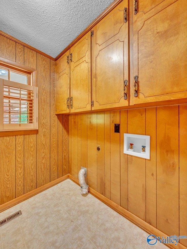 1913 Ruth St, Scottsboro, AL 35769 - clothes washing area with washer hookup, electric dryer hookup, visible vents, wood walls, and cabinet space
