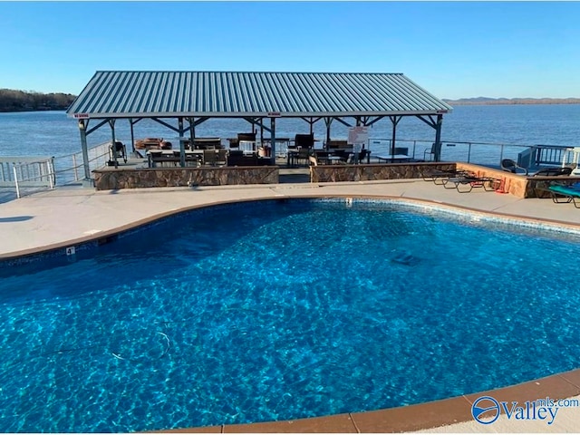 view of pool featuring a water view and a patio area