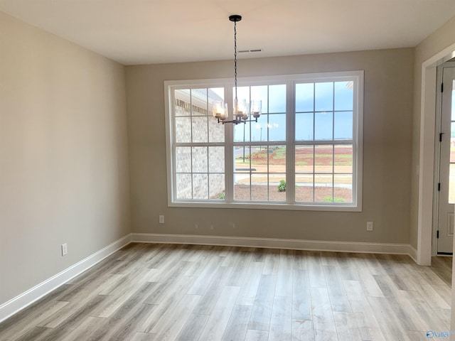 unfurnished dining area with baseboards, visible vents, a notable chandelier, and light wood finished floors