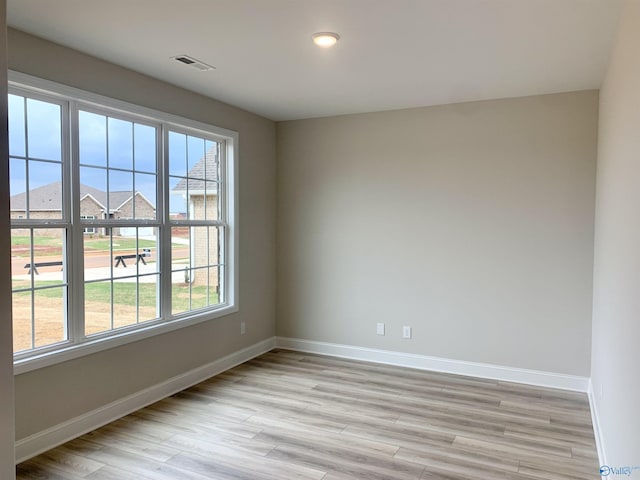 empty room featuring visible vents, plenty of natural light, light wood finished floors, and baseboards