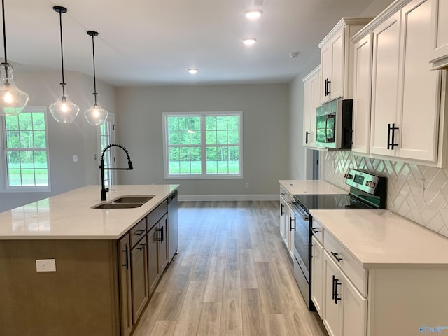 kitchen featuring stainless steel appliances, a wealth of natural light, backsplash, and a sink