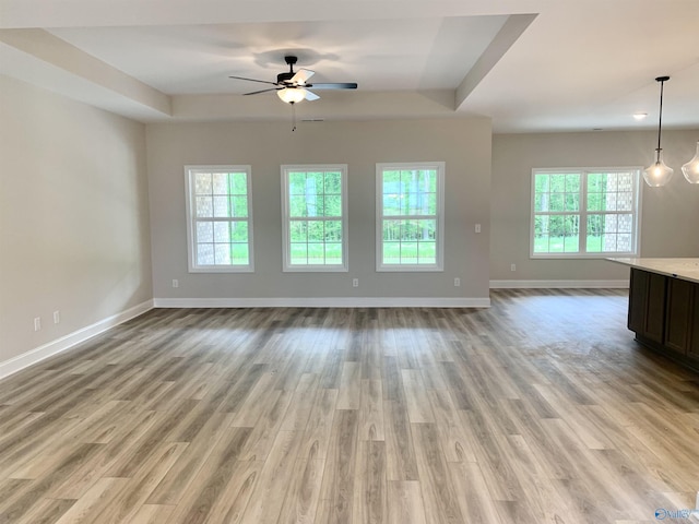 unfurnished living room featuring light wood finished floors, ceiling fan, baseboards, and a healthy amount of sunlight
