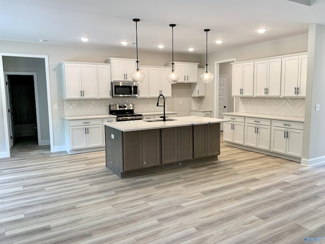 kitchen featuring white cabinetry, stainless steel appliances, backsplash, and a sink