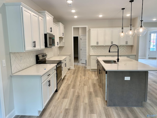 kitchen with light wood-style floors, appliances with stainless steel finishes, decorative backsplash, and a sink