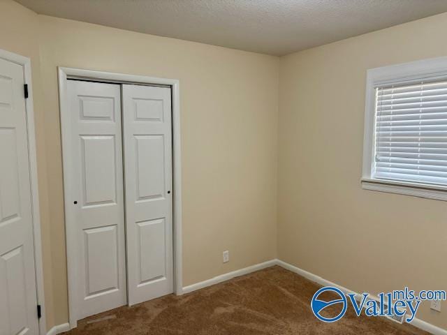 unfurnished bedroom with a textured ceiling, a closet, carpet flooring, and baseboards