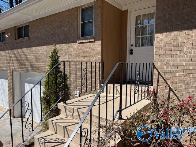 property entrance with a garage and brick siding