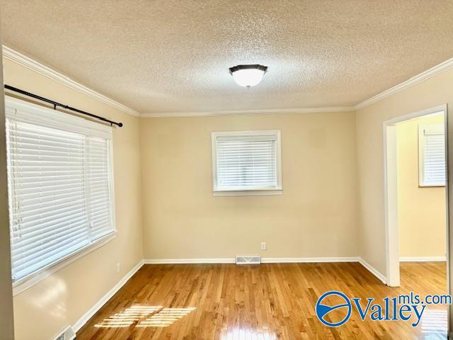 unfurnished room with baseboards, ornamental molding, and wood finished floors