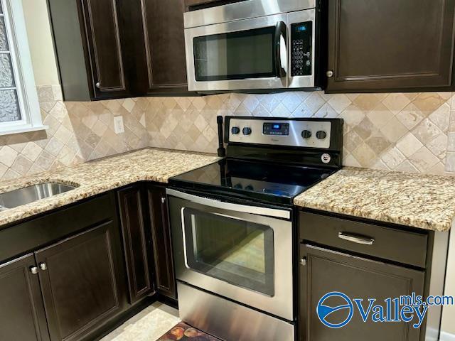 kitchen featuring appliances with stainless steel finishes, dark brown cabinetry, light stone counters, and tasteful backsplash