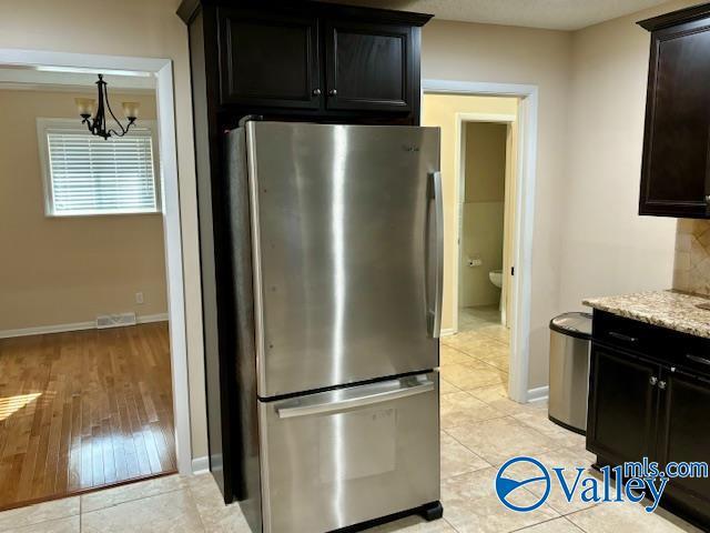 kitchen with light tile patterned floors, visible vents, an inviting chandelier, freestanding refrigerator, and baseboards