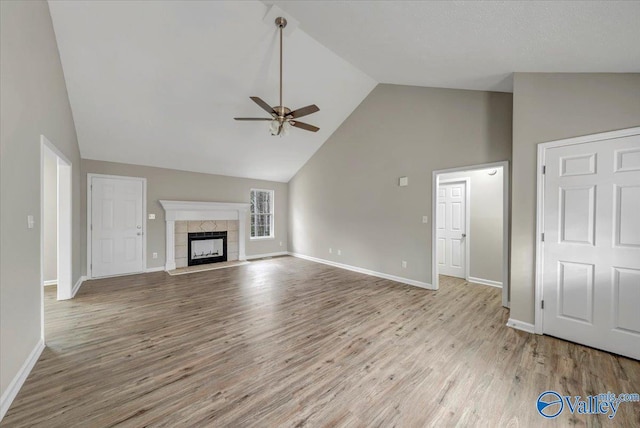 unfurnished living room featuring ceiling fan, high vaulted ceiling, a fireplace, and light hardwood / wood-style floors