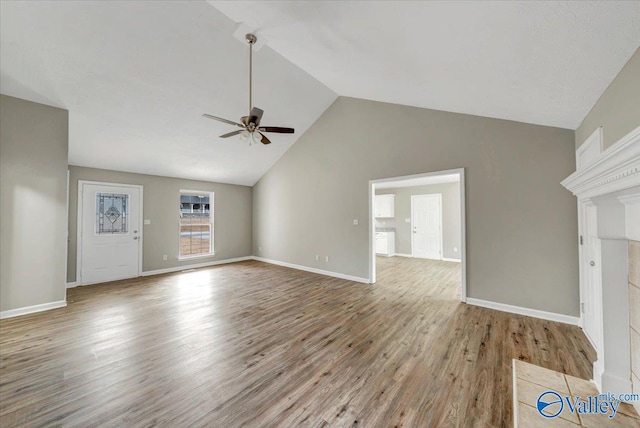 unfurnished living room featuring ceiling fan, a fireplace, high vaulted ceiling, and light wood-type flooring