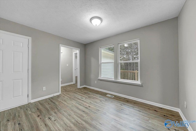 unfurnished bedroom with a textured ceiling and light wood-type flooring