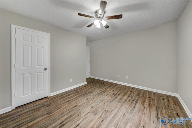 empty room with ceiling fan, wood-type flooring, and a textured ceiling