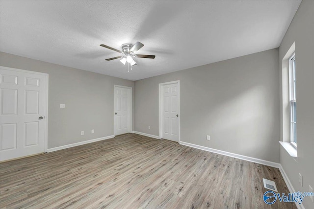 empty room with a textured ceiling, light hardwood / wood-style flooring, and ceiling fan