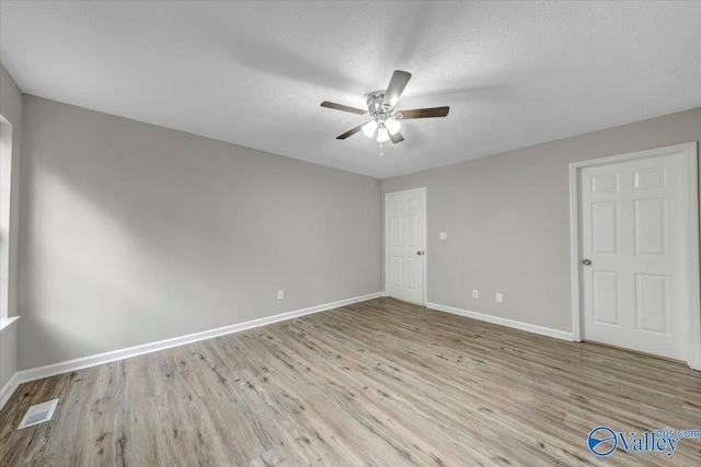 spare room with ceiling fan, a textured ceiling, and light hardwood / wood-style floors