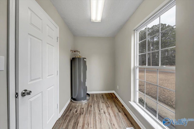 interior space with electric water heater, a textured ceiling, and light hardwood / wood-style flooring