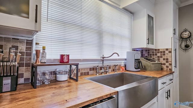 kitchen featuring butcher block countertops, a sink, white cabinetry, and tasteful backsplash