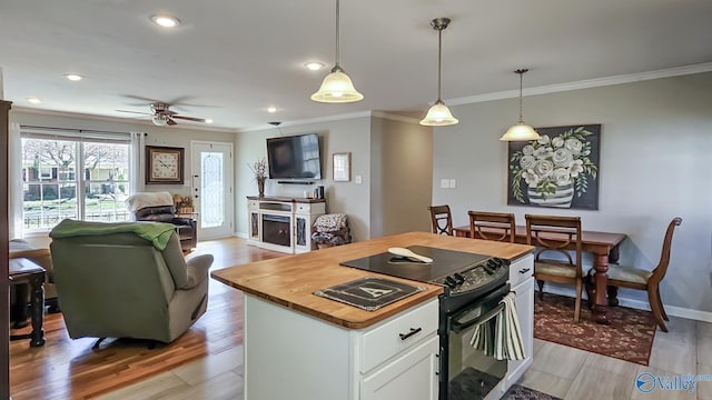 kitchen with light wood-type flooring, butcher block countertops, white cabinets, and black range with electric stovetop