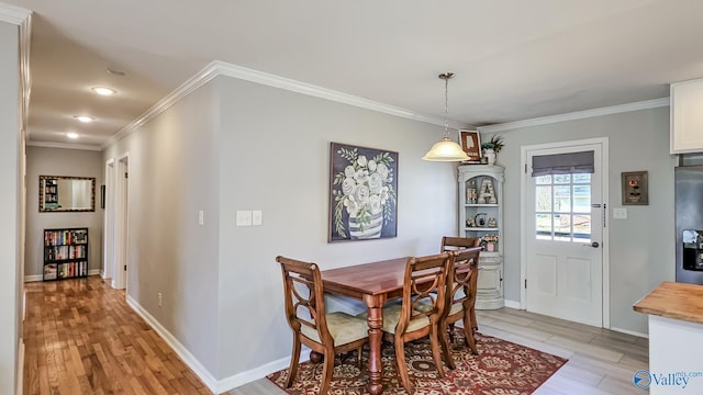 dining space with light wood-style floors, baseboards, and crown molding