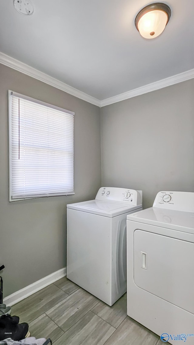 laundry area featuring baseboards, laundry area, washing machine and dryer, and crown molding