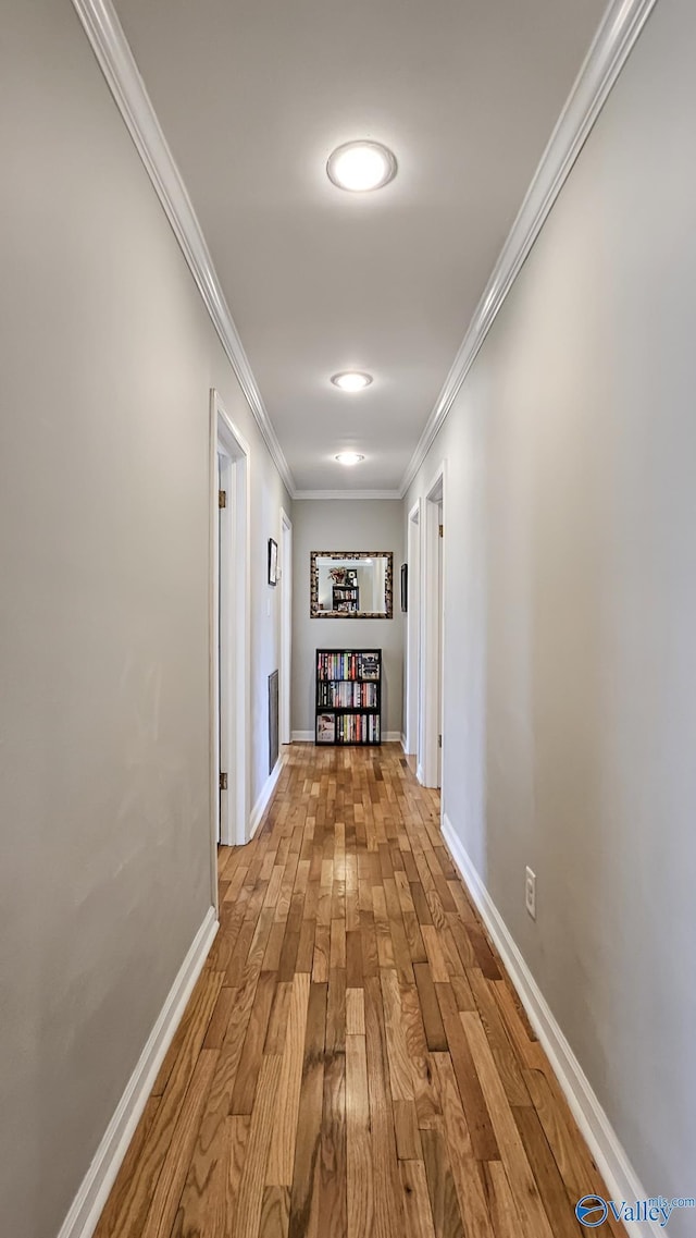 corridor with baseboards, wood finished floors, and crown molding