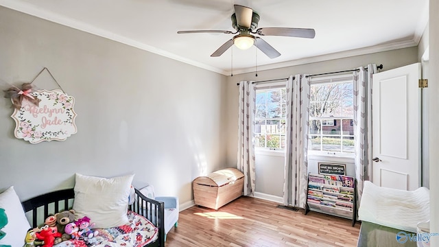 bedroom with baseboards, light wood finished floors, a ceiling fan, and crown molding