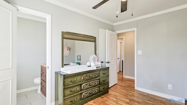 bedroom featuring ornamental molding, ensuite bath, light wood-style flooring, and baseboards