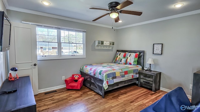 bedroom featuring baseboards, wood finished floors, visible vents, and crown molding