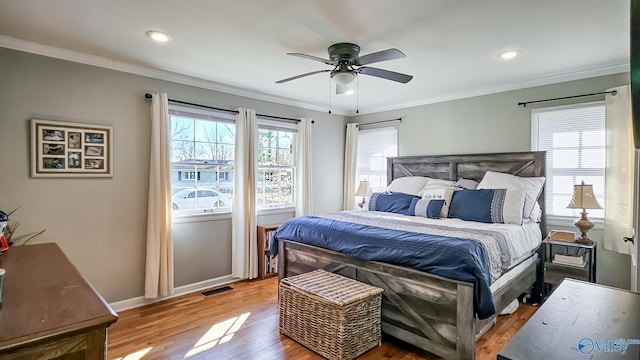 bedroom with ornamental molding, wood finished floors, visible vents, and baseboards