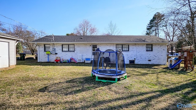 rear view of property with a trampoline, an outbuilding, a playground, and a yard