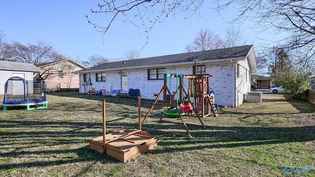 back of property with a trampoline, cooling unit, a playground, and a yard