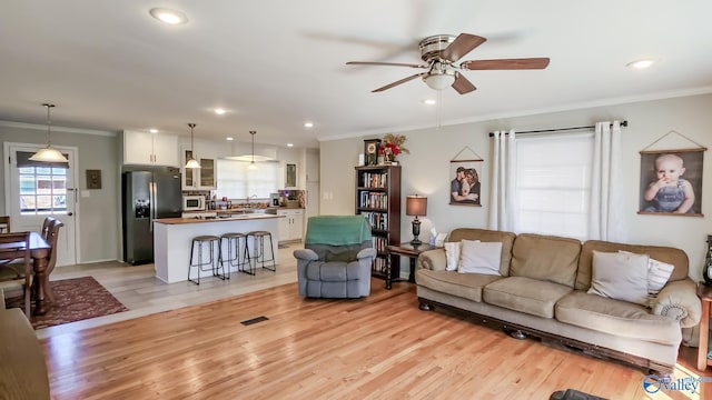 living area featuring light wood finished floors, recessed lighting, visible vents, ornamental molding, and ceiling fan