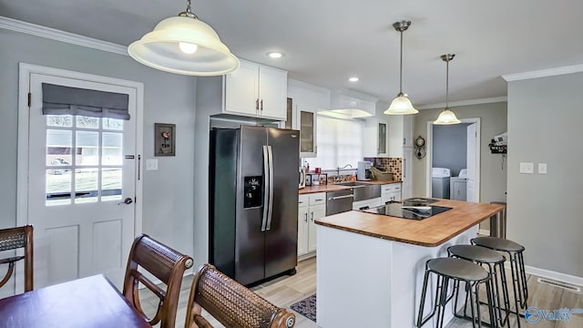 kitchen featuring stainless steel appliances, separate washer and dryer, white cabinetry, a kitchen bar, and crown molding