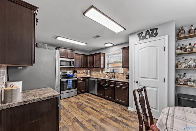 kitchen with a sink, visible vents, stainless steel appliances, dark brown cabinetry, and backsplash