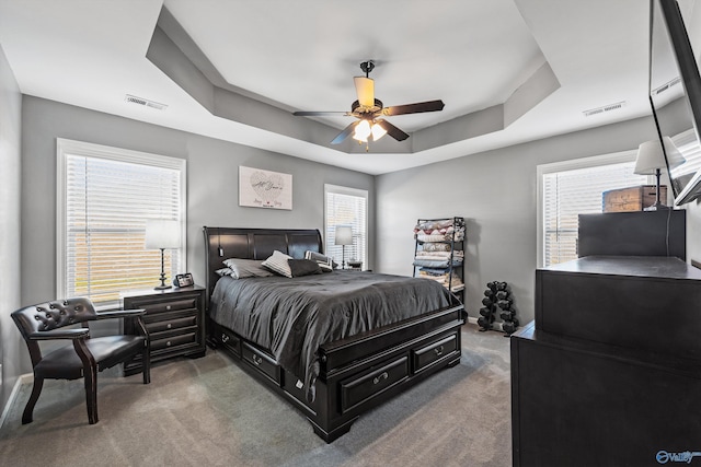 bedroom with carpet, visible vents, a raised ceiling, and baseboards