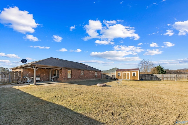 rear view of house with a yard, a patio, a storage unit, and a fenced backyard