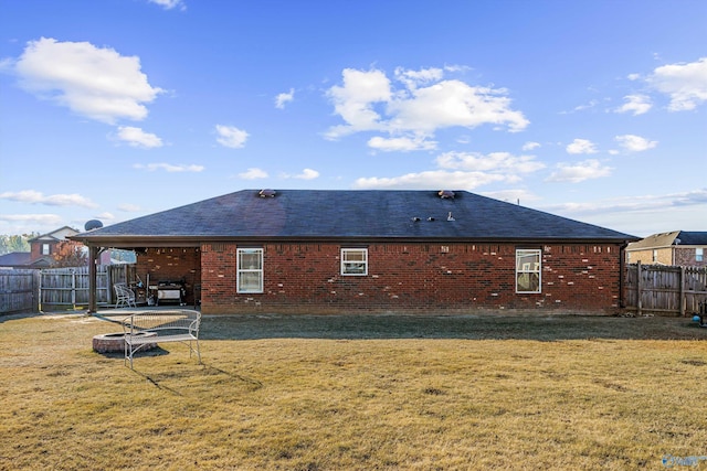 back of house featuring brick siding, a fenced backyard, and a lawn