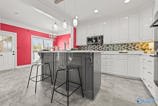 130 Kingswood Dr, Huntsville, AL 35806 - kitchen featuring stainless steel microwave, white cabinets, marble finish floor, and a breakfast bar area