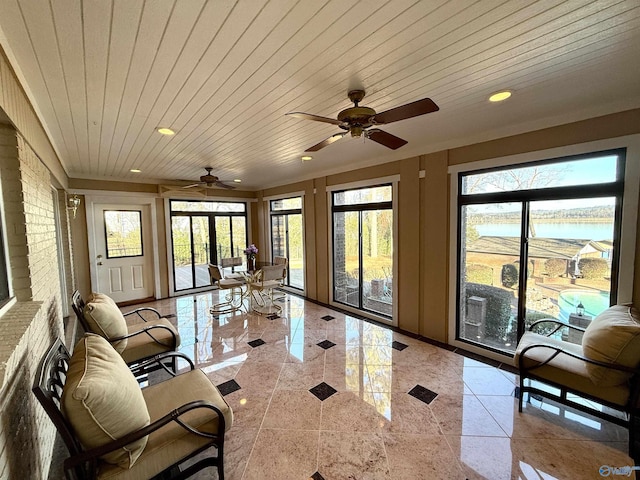 sunroom with ceiling fan, a water view, and wood ceiling