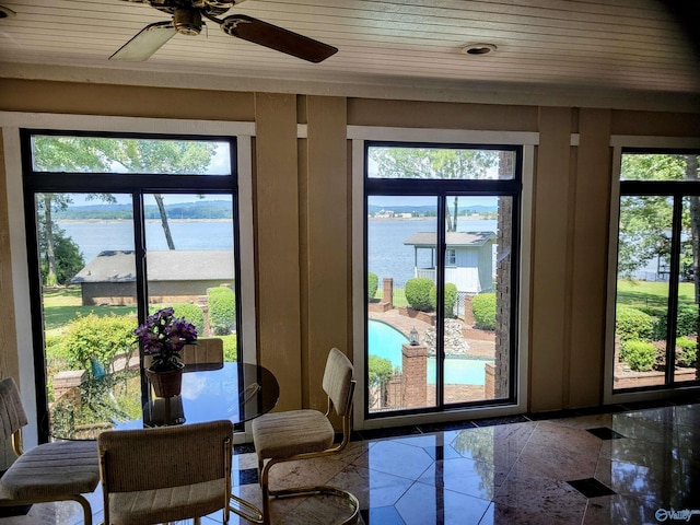 doorway featuring ceiling fan, tile patterned floors, a healthy amount of sunlight, and a water view