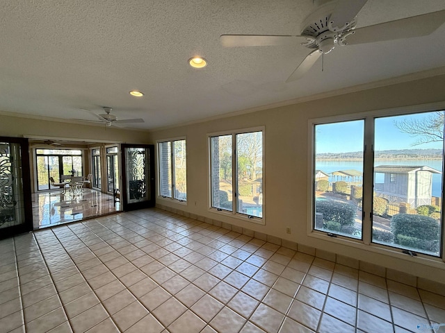 spare room with a textured ceiling, ornamental molding, a water view, and light tile patterned flooring