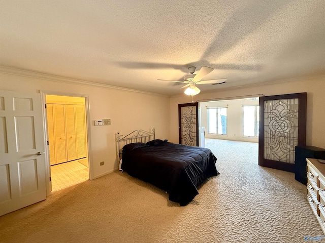 carpeted bedroom with a textured ceiling, ceiling fan, ornamental molding, and a closet