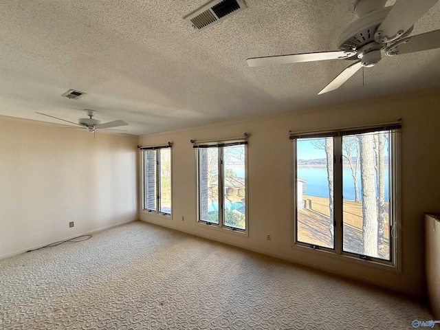 unfurnished room featuring a textured ceiling, ceiling fan, a water view, and light colored carpet